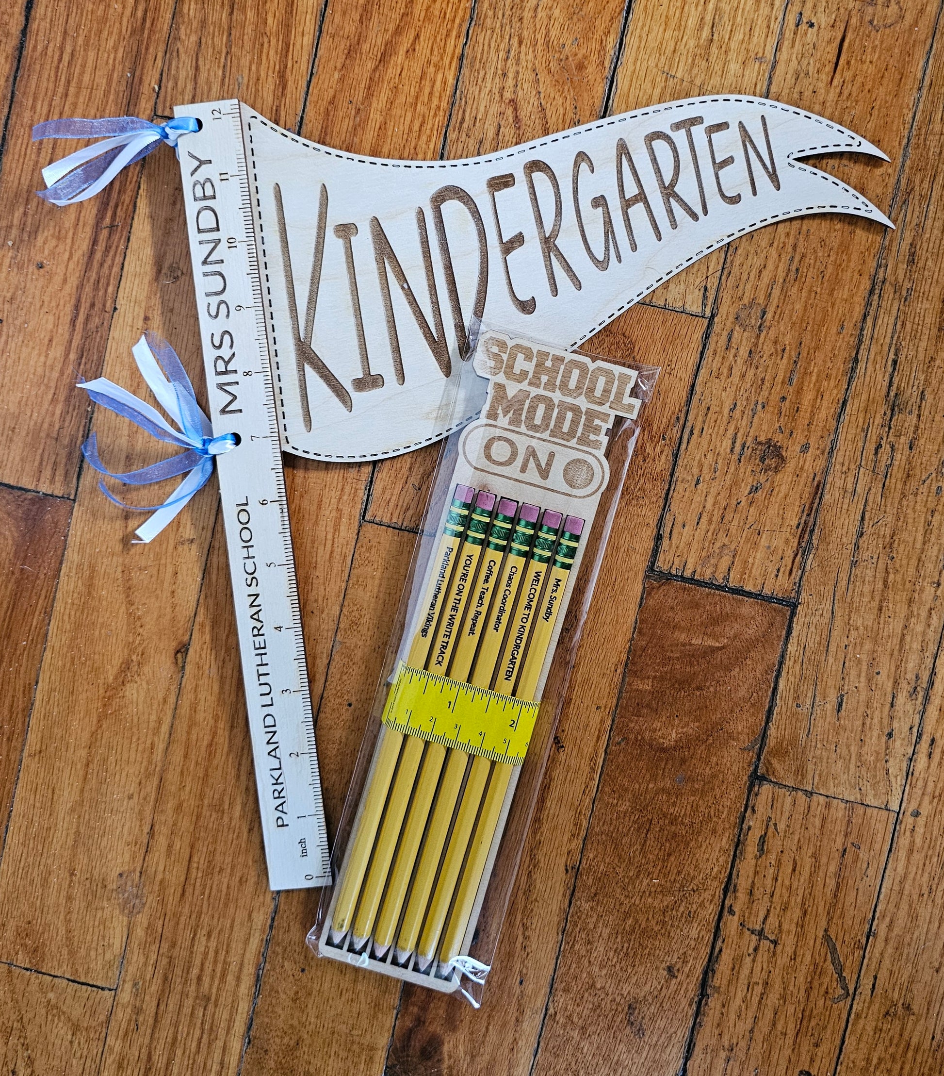 Celebrate the first day of school in style with our School Pennant Gift Set! Featuring a personalized ruler handle and a school color ribbon accent, this set is perfect for showing off your school spirit. Don't miss out on this fun and unique way to mark the beginning of a new school year!  Score extra credit with our Optional add-on of our Personalized 6 pc Pencil set and backer for added fun (and functionality). Don't miss out on this quirky and unique gift combo perfect for any student or teacher.&nbsp; 