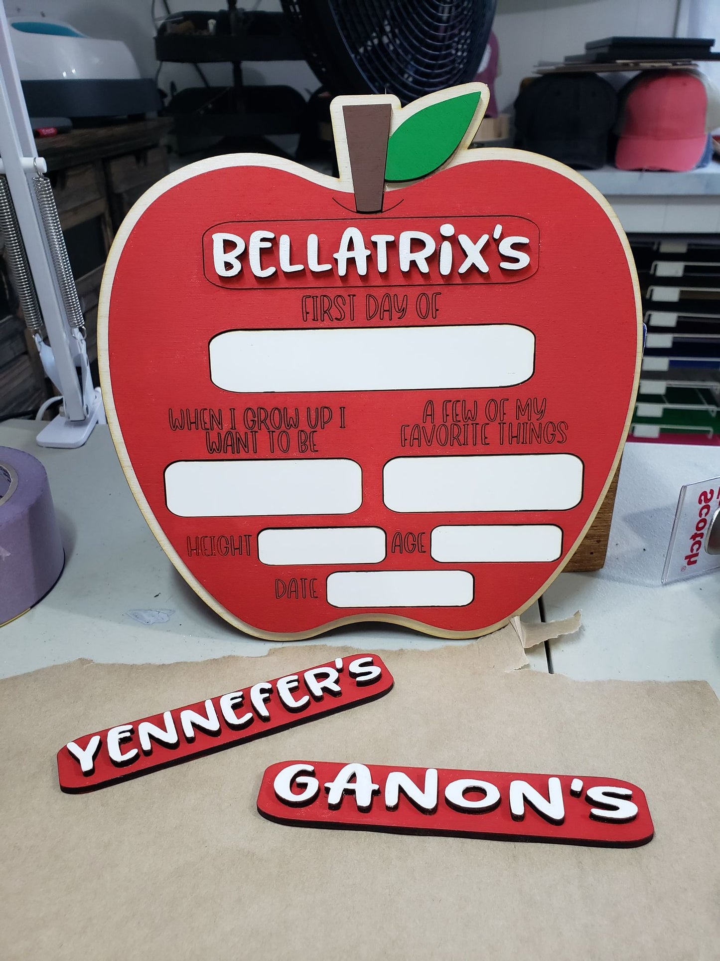 Capture your little one's first day of school memories in style with this custom birch wood Apple Photo Prop! It features one removable nameplate and 9 dry erase slots to re-use year after year. Details such as age, height, date, favorite things, and future aspirations can be written directly onto the sign. You can also request a permanent nameplate in the notes section. 9 3/4" wide by 8 3/8" tall.
