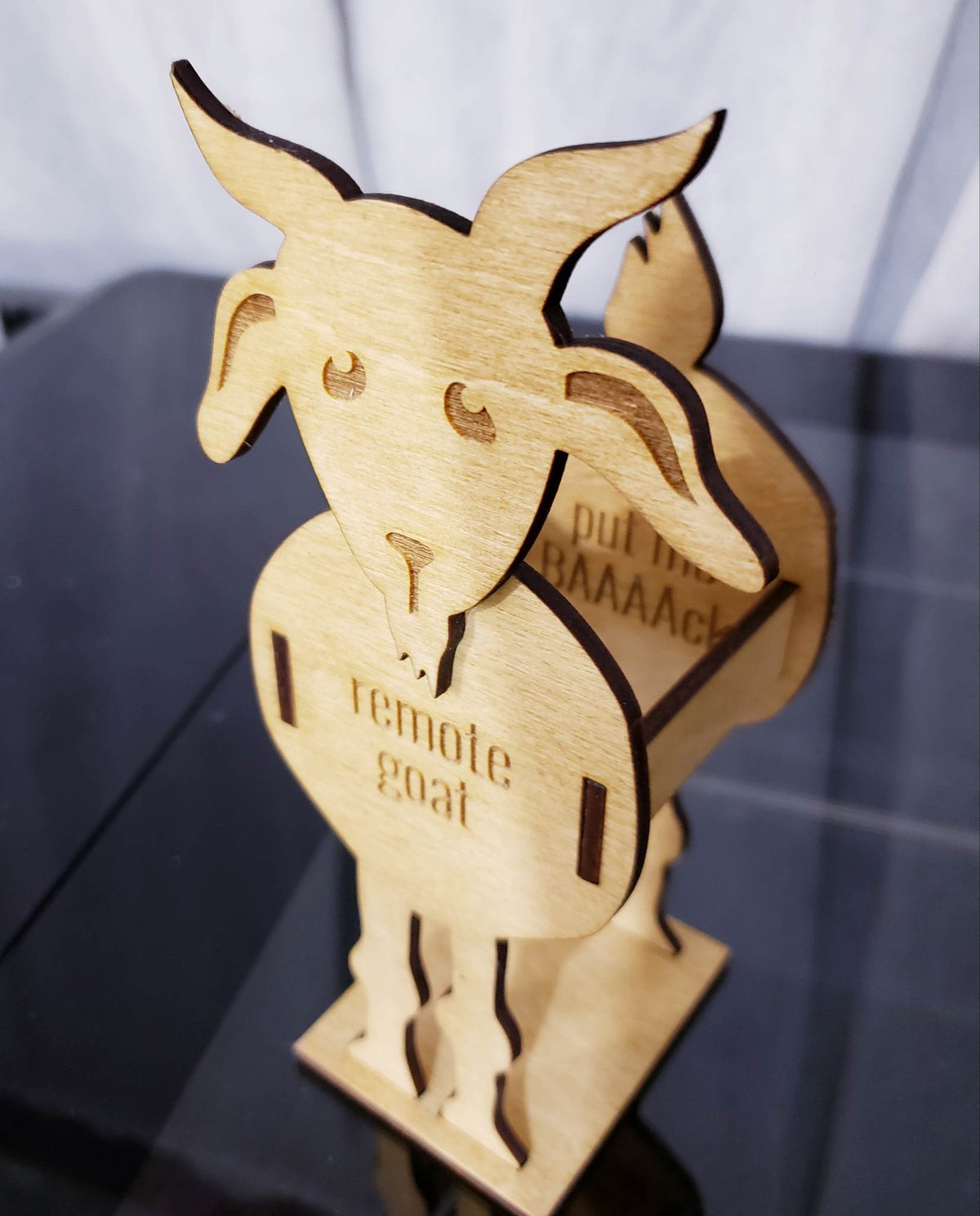 Remote Goat is the perfect addition to any living room, providing a safe and secure place to store 1-2 small remotes or 1 larger one. It features a reminder to help you remember to put remotes back into their holder, and its maple-stained birch wood construction is durable and stylish. This thoughtful gift ships in 5-7 days.