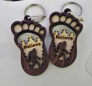 This unique Bigfoot keychain is laser cut from two layers of birch wood and finished with a walnut stain and natural accents. It measures approximately 3" x 1.5" including the key ring, and ships within 5 to 7 days. Show your belief in Bigfoot with this quality and stylish keychain.