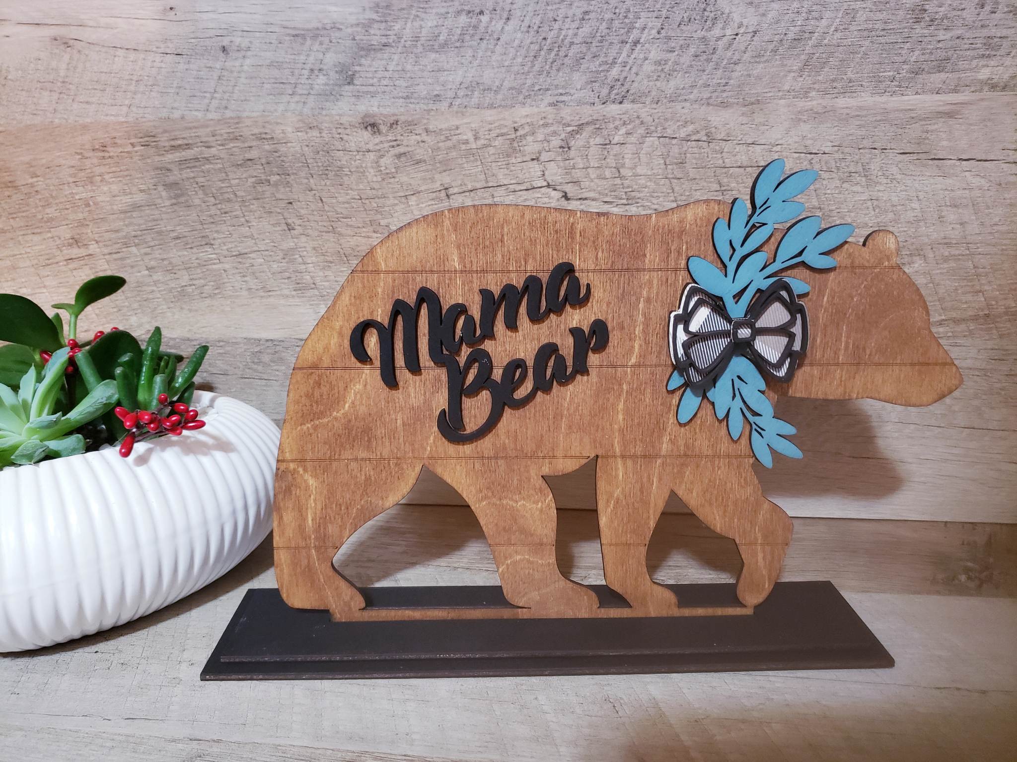 This Mama Bear Shelf Sitter is crafted from stained birch wood, with the option to add up to 6 personalized cubs. Measuring approximately 10.5 in x 8 in, it ships in 5 to 7 days