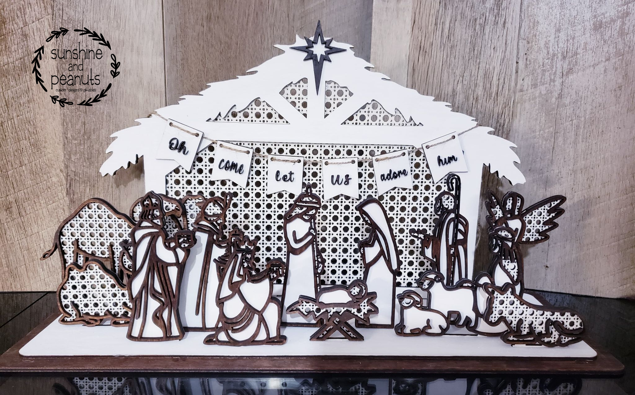 Bring a touch of timeless elegance to your holiday decor with this beautiful Rattan Nativity Scene. Laser cut from Birch, every piece is hand-painted with White acrylic and stained with a Walnut trim, forming a lovely miniature diorama. This set of 16 pieces includes the stable, draping banner, 3 camels, 3 Wise Men, 2 shepherds, a donkey, an angel, Mary, Joseph, and Baby Jesus in the manger. Measures 10" high, 18" wide, and 6" deep when assembled. Order now and have your Nativity Scene ready in 5-7 days!