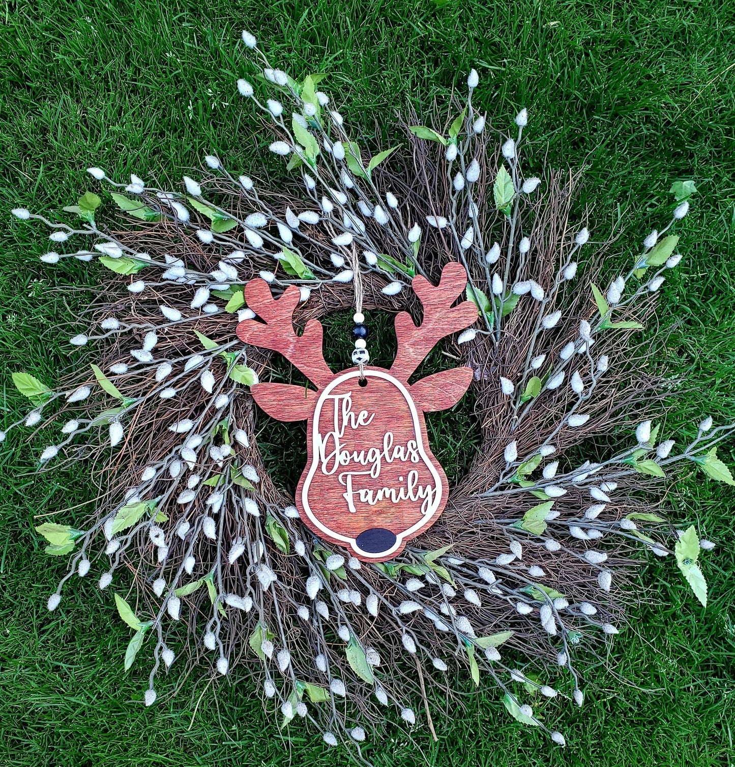 Don't miss out on this Personalized Reindeer Family Name sign. It is the perfect accent for your front door or your holiday wreath.   (Matches perfectly with our Personalized Reindeer ornaments.)    Each sign measures approx. 8.5" wide by 10.5" tall, not including the beads  They are laser cut from Birch wood and are stained a beautiful mixture of cherry and maple, with hand painted accents using acrylic and chalk paints.  Choose from either a Black or Red nose and add your Family name. 